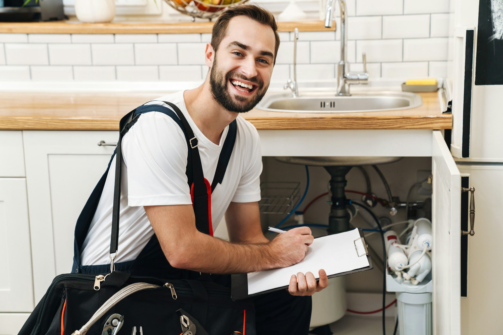 Image of plumber man with equipment and clipboard working in apartment